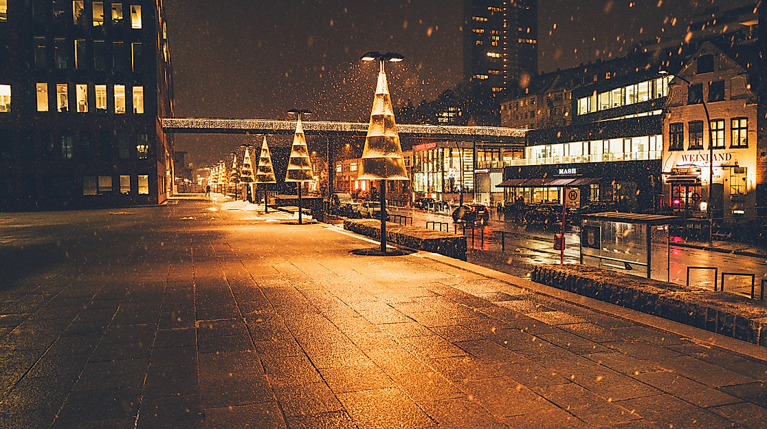 Christmas lights reflecting on wet cobblestones at night in a festively lit Hamburg street