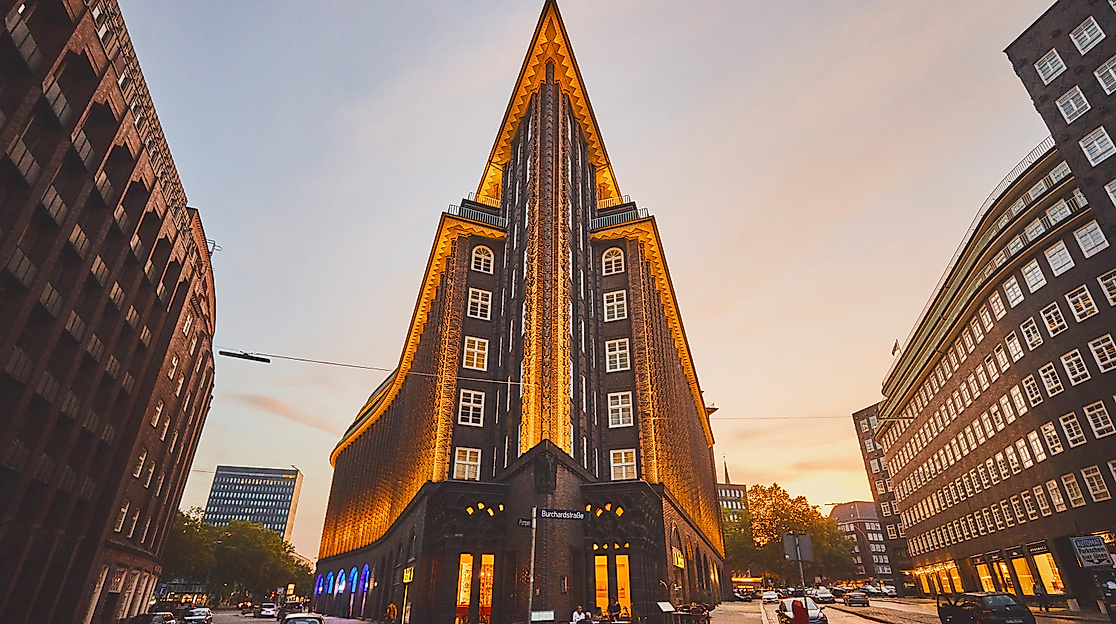 Spitz zulaufende Front des beleuchteten Chilehauses in Hamburg bei Sonnenuntergang