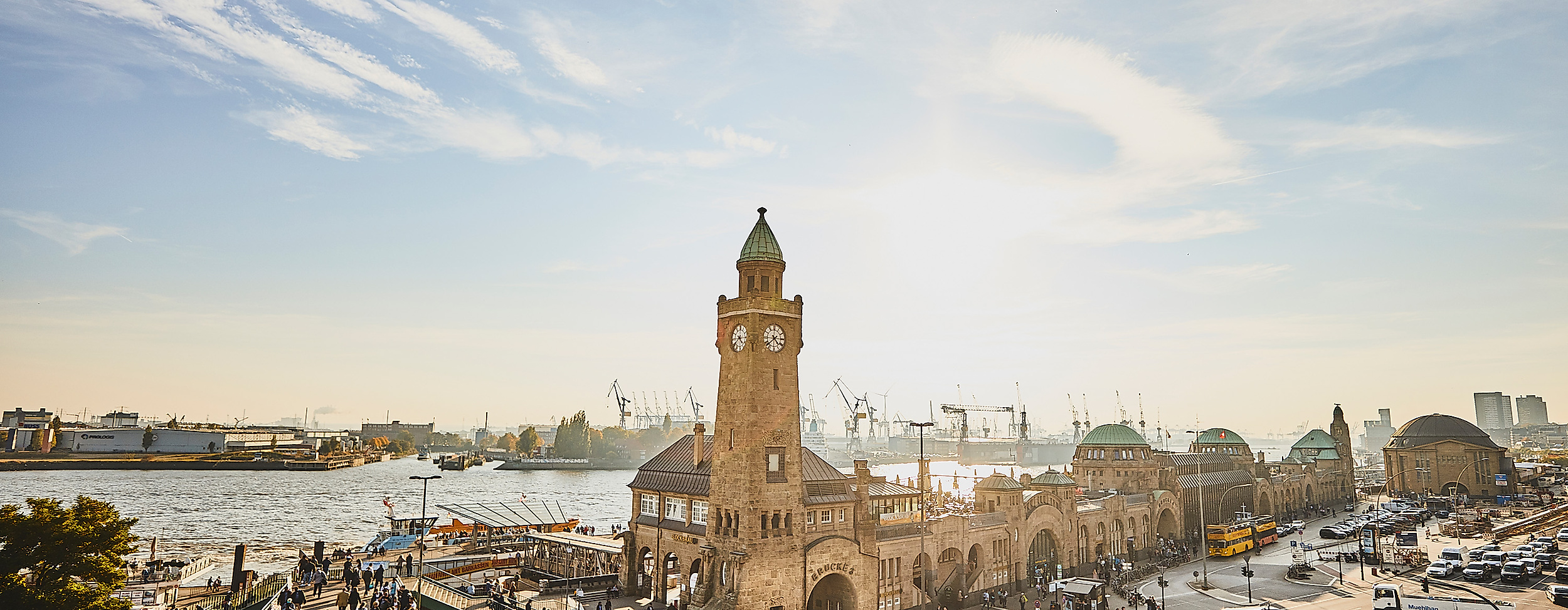 Landungsbrücken mit Uhrturm und Elbe im goldenen Licht der tief stehenden Abendsonne