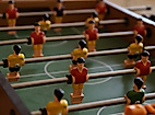Nahaufnahme eines Tischkickers mit rot-gelben Spielfiguren auf grünem Spielfeld