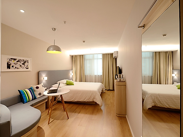 Modern eingerichtetes Hotelzimmer mit Doppelbett, Sitzecke und Schreibtisch in warmem Licht.