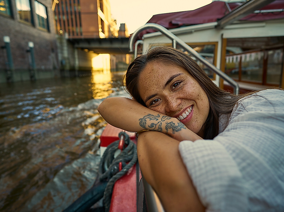 A young woman is leaning against the deck of a boat.