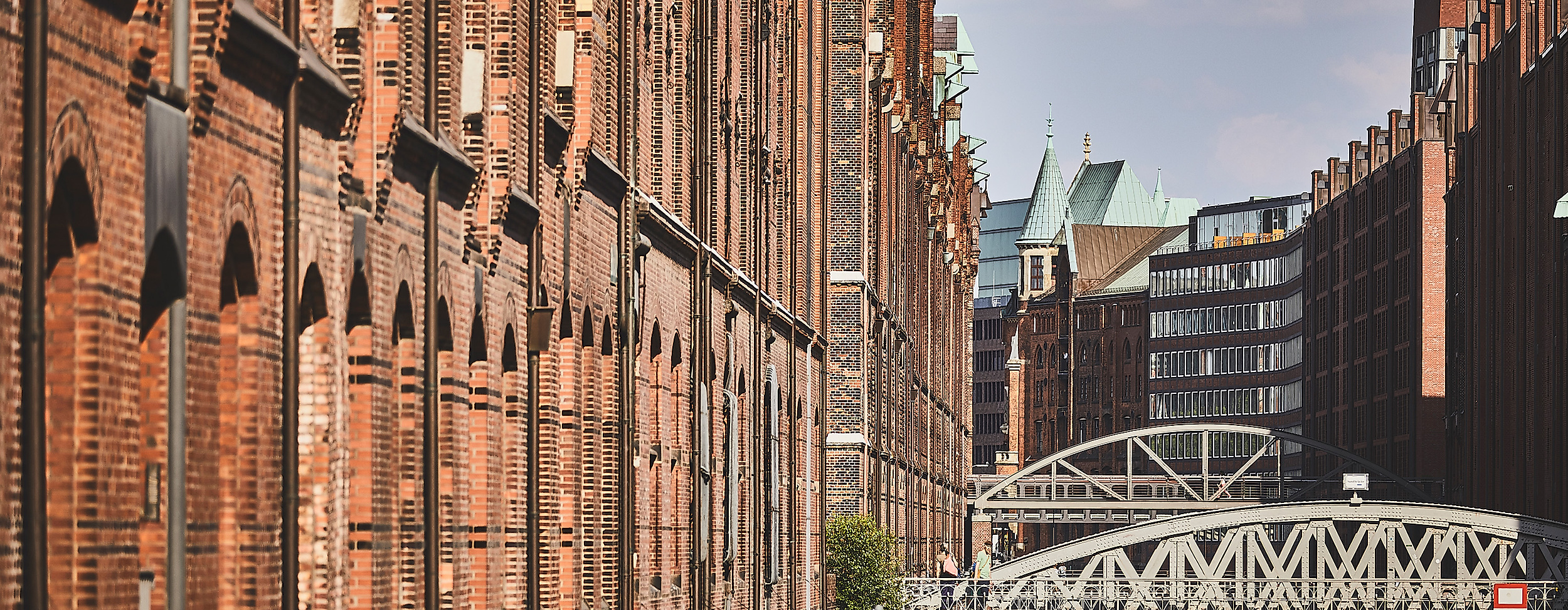 Backsteinfassaden der Hamburger Speicherstadt mit Wasserlauf und Brücke bei Tageslicht
