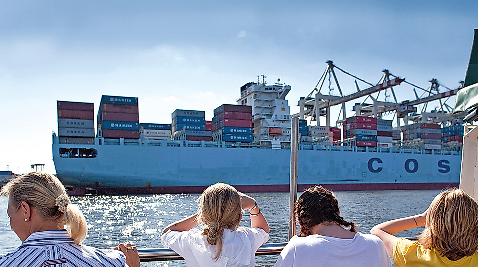 Familie steht an der Elbe und schaut auf Container Schiff