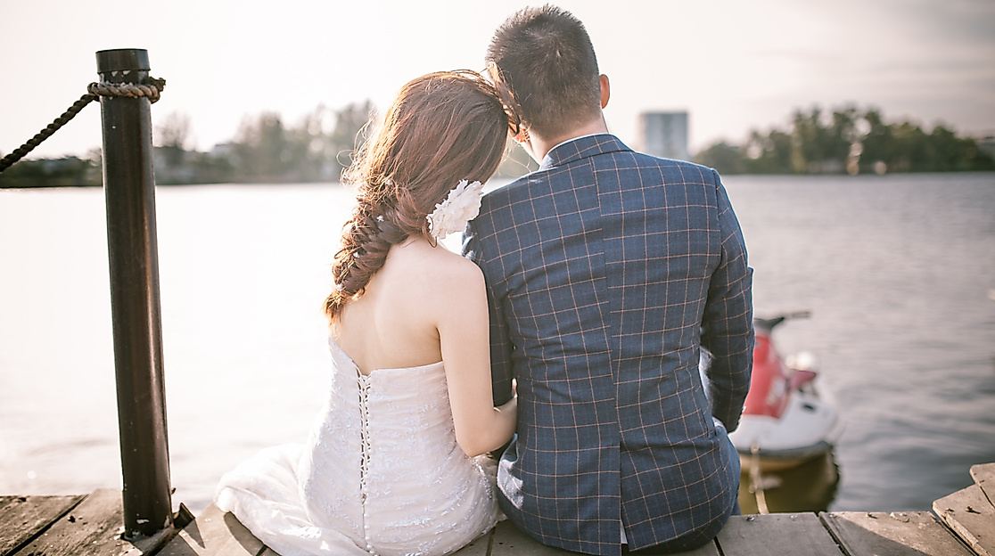 Hochzeitspaar sitzt auf einem Steg am Wasser und genießt einen ruhigen Moment zu zweit in Hamburg