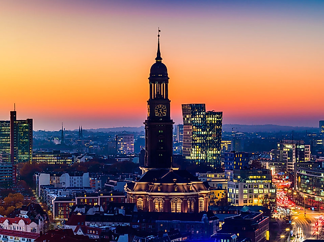 Barocker Turm der Hamburger Michel-Kirche vor Skyline bei Sonnenuntergang.