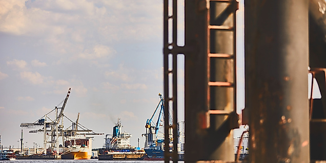 Industrielle Hafenansicht in Hamburg mit rostiger Leiter im Vordergrund und Kränen im Hintergrund