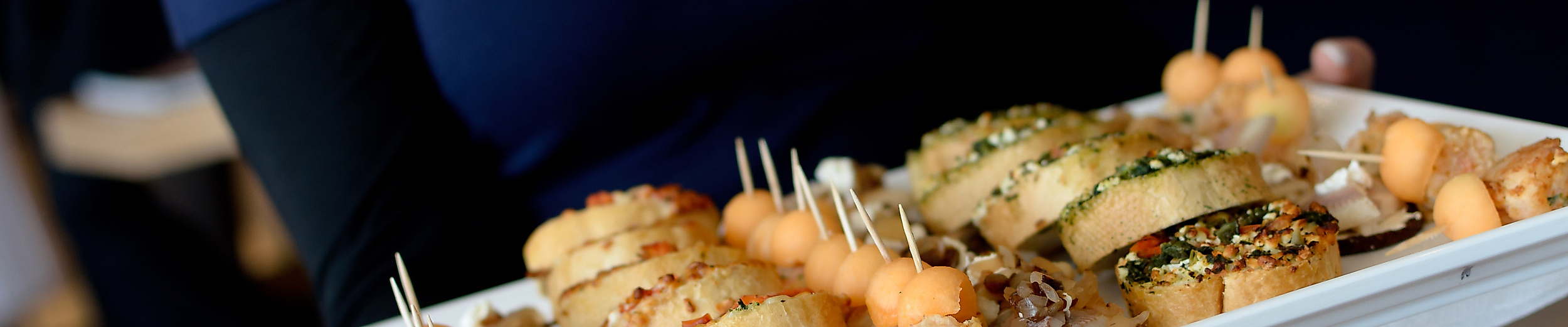 Person mit Hamburg-Shirt serviert Platte mit Fischbrötchen und Fingerfood-Häppchen