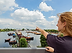 Frau blickt auf historische Schiffe im Hamburger Hafen und zeigt in die Ferne bei sonnigem Wetter