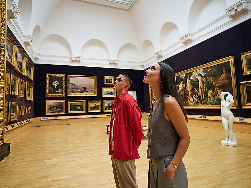 Two young adults are looking at pictures in a historic hall at the Kunsthalle Hamburg.